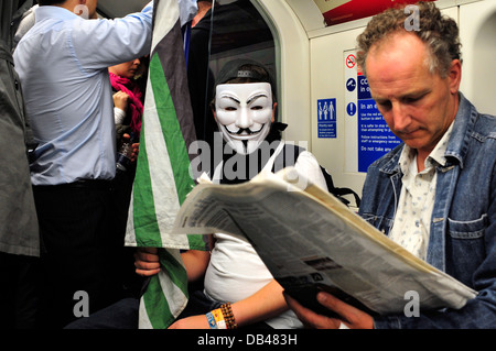 Ein Mann mit einer anonymen Maske in der u-Bahn. London, Vereinigtes Königreich. Stockfoto