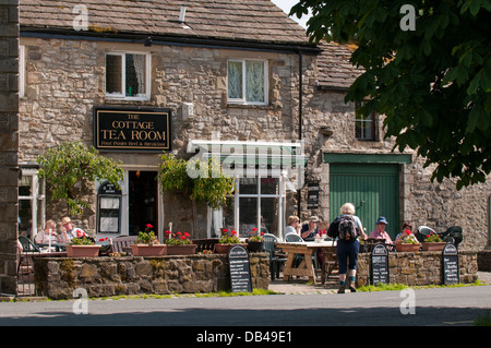 Menschen Erfrischungen genießen, Sitzen, Essen & Trinken im Freien in der Sonne - außerhalb der Hütte Teestube, Kettlewell, North Yorkshire, England, UK. Stockfoto