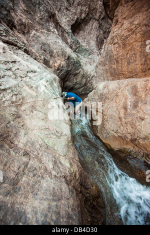 Mann absteigend Wüste Schlucht mit Wasser durchlaufen. Stockfoto