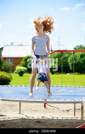 Schöne junge Mutter und Töchterchen hüpfen auf dem Trampolin Stockfoto