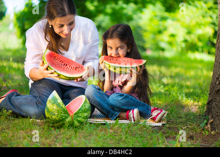 Glückliche hispanische Familie Essen Wassermelone im park Stockfoto