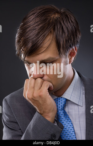 Porträt der schönen jungen Geschäftsmann vor einem grauen Hintergrund denken Stockfoto