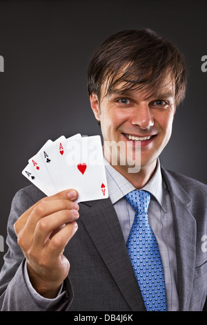 Porträt der Geschäftsmann hält vier Asse auf grauem Hintergrund Stockfoto