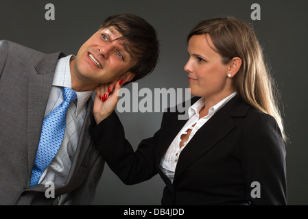 eine Hand zieht eine Geschäftsmann Ohr auf grau Stockfoto