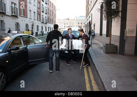 Irische Eurovision Hoffnungsträger Jedward aka John Grimes und Edward Grimes (Edward auf Krücken) verlassen Dublins Morrison Hotel nach einem Treffen mit berühmten Designer Louis Copeland Kleidung. Als sie Copeland trafen sich mit den Jungs ankamen und alle 3 in einem privaten Raum verschwand, könnte passend für Eurovision Anzüge? Dublin, Irland - 28.04.11 Stockfoto