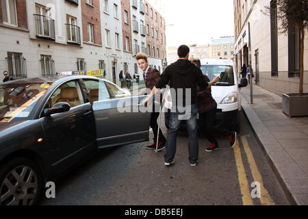 Irische Eurovision Hoffnungsträger Jedward aka John Grimes und Edward Grimes (Edward auf Krücken) verlassen Dublins Morrison Hotel nach einem Treffen mit berühmten Designer Louis Copeland Kleidung. Als sie ankamen Copeland trafen sich mit den Jungs und alle 3 verschwand ein p Stockfoto