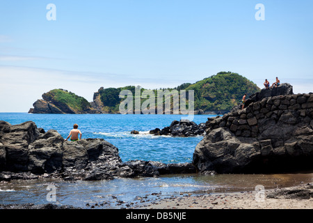 Jungs spielen auf den Felsen gegenüber der Insel von Vila Franca Küste São Miguel. Stockfoto