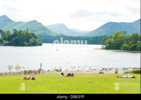 Touristen in Crow Park Sonnenbaden mit Blick auf die Borrowdale Fells und See Derwentwater in Keswick, Lake District. Stockfoto