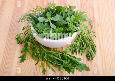 Mörtel mit Farbe Pfeffer, frischer Feldsalat, Rucola, Thymian, Majoran und Dill auf Holzbrett Stockfoto