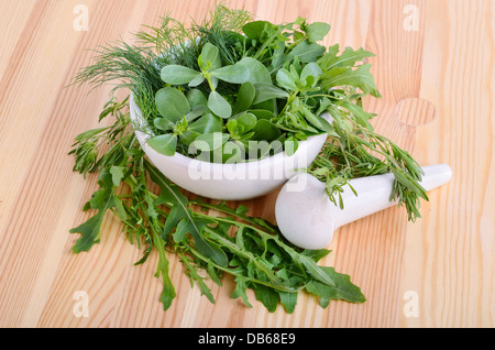 Mörtel mit Farbe Pfeffer, frischer Feldsalat, Rucola, Thymian, Majoran und Dill auf Holzbrett Stockfoto