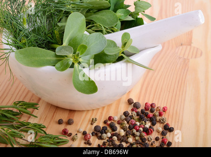 Mörtel mit Farbe Pfeffer, frischer Feldsalat, Rucola, Thymian, Majoran und Dill auf Holzbrett Stockfoto