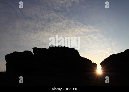 Der Sonnenaufgang sehen durch eine Lücke in den Felsen am Almscliffe Felsen, in der Nähe von Harrogate in North Yorkshire, England Stockfoto