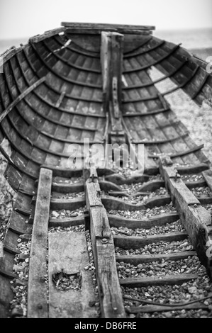 Altes Holzboot, das am Strand verrottet wurde, zeigte Löcher an den Seiten und am Boden Stockfoto