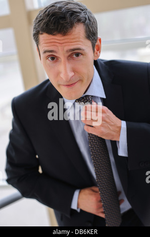 Manager korrigiert Krawatte mit einem Gesichtsausdruck, impliziert einen weitere showdown Stockfoto