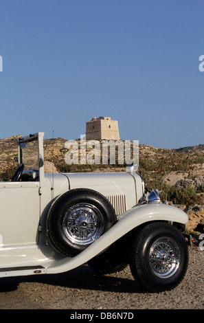 Blick über einen 1930er Ford Modell DeLuxe Limo in Richtung Img Dwejra Tower manchmal als Qawra Tower einen kleinen Wachturm in Dwejra Bay auf der Insel Gozo in Malta bekannt Stockfoto