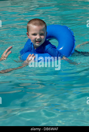 Ein sechs Jahre alter Junge mit Autismus Lächeln während des Spielens mit seinem Vater in den Pool. Stockfoto