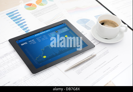 Moderne digital-Tablette mit Börse Datenanwendung auf einem Schreibtisch mit einer Tasse Kaffee, Stift, einige Papiere und Dokumente Stockfoto