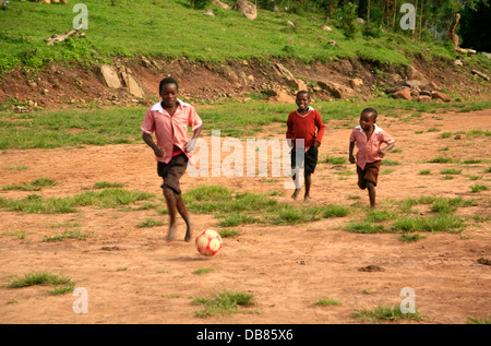 Afrikanische Kinder spielen Fußball auf einem staubigen Feld in Uganda Stockfoto