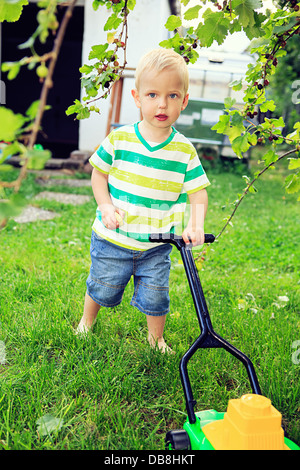 kleiner Junge spielt mit Spielzeug Werkzeuge im Hinterhof Stockfoto