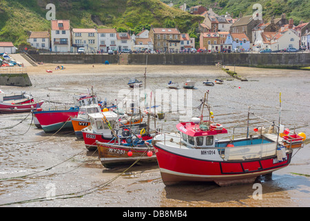 Eine Linie der Fischerboote liegen auf dem Sand bei Ebbe in Staithes Hafen North Yorkshire Stockfoto