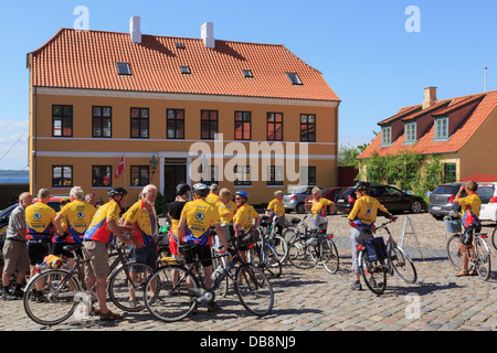 Fahrrad-Club von senior Radfahrern mit Fahrrädern durch Art Society Tinghuset Gerichtsgebäude in gepflasterten Marktplatz in Ebeltoft Dänemark Stockfoto