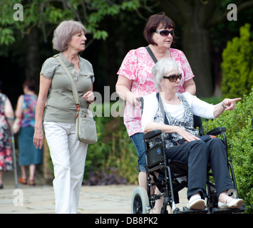 verschiedene ältere reife Erwachsene zu Fuß im Park erwachsenen Mannes Erwachsene Frauen und Rollstuhl Stockfoto