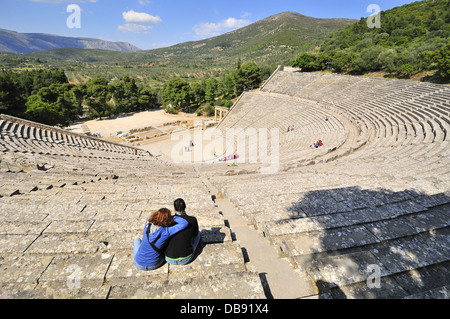 Altes Theater von Epidavros mit einem Paar auf den Terrassen, die Platz für bis zu 15.000 Personen bieten, Peloponnes, Griechenland Stockfoto