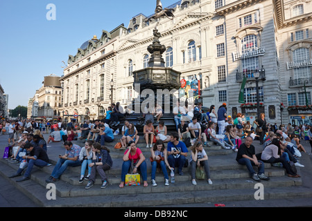 Touristen und Besucher sitzen auf den Stufen des Eros-Statue am Picadilly Circus London England UK Stockfoto