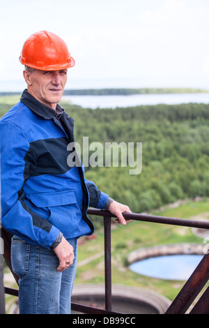 Kaukasische Arbeiter im schützenden einheitliche stehen für hohe Wartungsbühne Stockfoto
