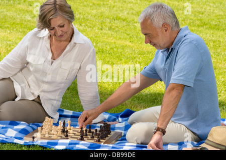 Pensionierte älteres Paar beim Schachspiel im Park sitzen Decke Rasen Stockfoto