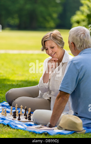 Ältere Freunde paar beim Schachspiel im Park am sonnigen Tag Stockfoto