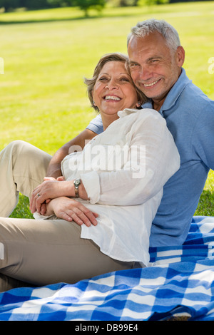 Gerne älteres Paar im Park sitzen auf Decke Stockfoto