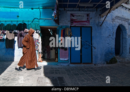 Mann vorbei ein Textilgeschäft in der Medina. Chefchaouen, Rif-Region, Marokko Stockfoto