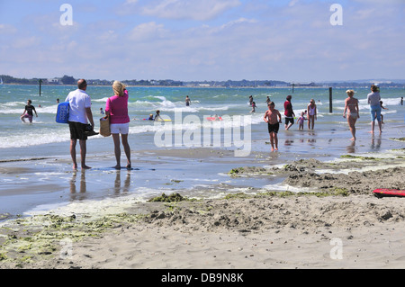 Paar mit Schwimmer auf sonnigen West Wittering blaue Flagge Strand nr. Chichester, West Sussex, UK mit Hayling Island in Ferne Stockfoto