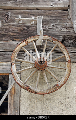 Alte hölzerne Rad an einer Holzwand der Scheune hängen Stockfoto