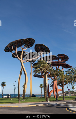 Große Kiefer Baum an der Strandpromenade von La Pineda Löwenskulptur. Stockfoto