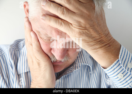 ältere Mann Schmerzen hält seinen Kopf mit beiden Händen Stockfoto