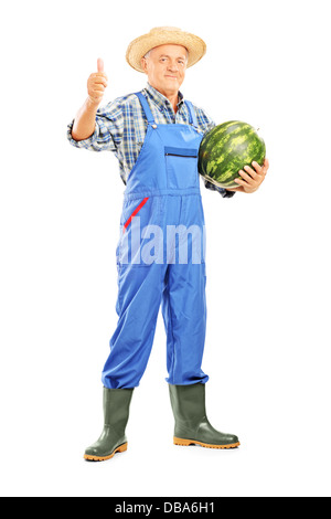 In voller Länge Portrait eines lächelnden Bauern halten eine Wassermelone und Daumen aufgeben Stockfoto