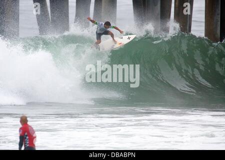 Huntington Beach, CA, USA. 26. Juli 2013. 26. Juli 2013: Michel Bourez von Französisch-Polynesien ist ein Schwimmer wie Kelly Slater im Vordergrund während Förderwettbewerbs Vans uns Open of Surfing in Huntington Beach, CA. Kredit Uhren: Csm/Alamy Live-Nachrichten Stockfoto