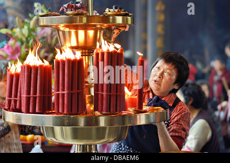 Eine Frau entfacht das Feuer im Longshan Tempel in Taipei, Taiwan. Stockfoto