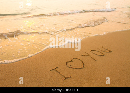 Ich liebe dich - Inschrift auf dem Strandsand, weiche Surfwelle. Stockfoto