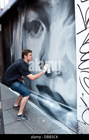 Graffiti-Künstler bei der Arbeit am Wandbild. Stockfoto