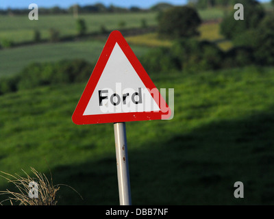 Ein rotes Dreiecksschild, das vor einem Ford warnt. Stockfoto