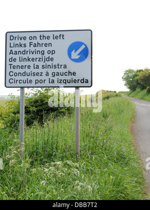 Ein Schild mit der Aufschrift "Fahren links" in mehreren Sprachen. Stockfoto