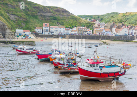 Eine Linie der Fischerboote liegen auf dem Sand bei Ebbe in Staithes Hafen North Yorkshire Stockfoto