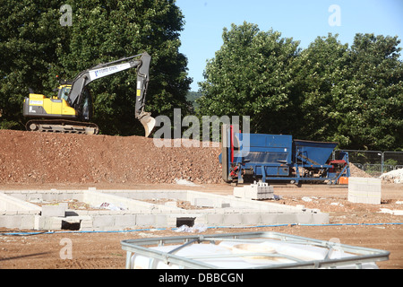 Bagger und vernichtende Maschine auf einem Wohnbau vor Ort in Somerset, England. Juli 2013 Stockfoto