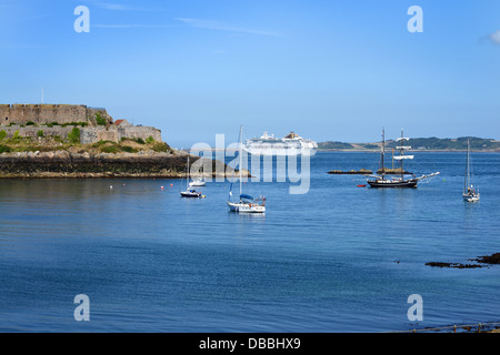 Boote in Havelet Bay übersehen von Castle Cornet und eine Kreuzfahrt Schiff in der Ferne. St Peter Port, Guernsey Stockfoto