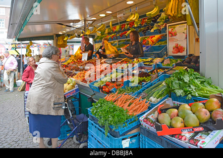 Stadt Maastricht Obst und Gemüse auf schrägen, farbenfrohen Verkaufsständen mit Mitarbeitern, die grauhaarige Frauen auf dem Marktplatz der Stadt Niederlande EU servieren Stockfoto