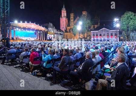 Maastricht Vrijthof Square Limburg aus nächster Nähe zahlendes Publikum, das André Rieu Abendmusik-Konzert-Event mit Flutlicht an Bäumen und Gebäuden ansieht und hört Stockfoto