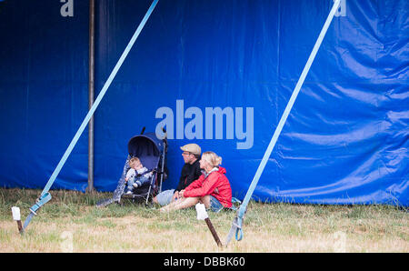 Malmesbury, Wiltshire, UK. 27. Juli 2013. Eine junge Familie Tierheime vor dem Regen beim WOMAD-Festival in Charlton Park in der Nähe von Malmesbury in Wiltshire. Die World Music Festival zieht fast 40.000 Menschen, die ländliche Lage. Kredit-27. Juli 2013: Adam Gasson/Alamy Live-Nachrichten Stockfoto